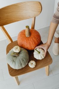 Kaboompics - Hand Arranging Pumpkins on a Wooden Chair