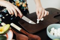 Kaboompics - Hands Chopping Garlic on a Dark Cutting Board with Fresh Ingredients