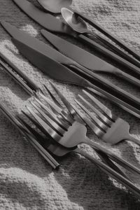 Kaboompics - Matte Steel Cutlery Flat Lay with Forks, Knives and Spoons on Textured Fabric