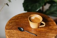 Kaboompics - Latte Cup and Black Spoon on a Round Wooden Table by the Window
