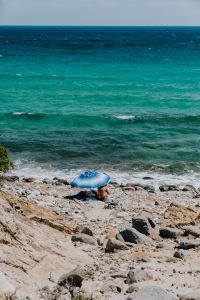 Kaboompics - Turquoise Waves and Blue Umbrella Along a Rocky Shoreline