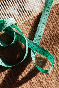 Kaboompics - Vertical Green Tape Measure with Printed Numbers on Two Fabric Textures