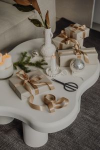 Kaboompics - Sculptural White Side Table with Neutral Christmas Gifts, Candles and Evergreen