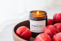 Kaboompics - Amber Soy Candle and Red Plums in a Wooden Bowl for Home Fragrance Branding
