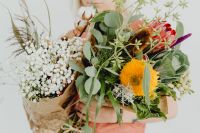 Kaboompics - A woman holds many different flowers and leaves in her arms