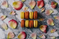 Kaboompics - Colorful French Macarons in Two Rows with Scattered Rose Petals on Marble