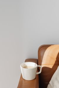 Kaboompics - Minimal Coffee Cup and Cognac Sofa with Sunlit Wall Copy Space for Editorial Layouts