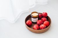 Kaboompics - Wooden Bowl of Red Plums and Scented Candle for Neutral Home Styling