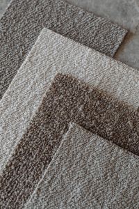 Kaboompics - Overlapping Neutral Bouclé Upholstery Fabric Swatches with Brown Accent