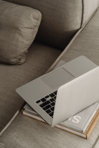 Kaboompics - Open Laptop and Books on a Textured Neutral Sofa, Remote Work Close-Up
