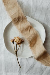 Kaboompics - Single Dried Rose on White Ceramic with Burlap Ribbon for Wedding Flat Lay