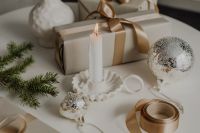 Kaboompics - Neutral Holiday Gift Wrapping with Ribbon Spool, Silver Bauble and Taper Candle