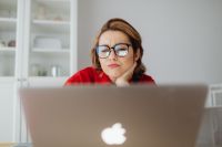 Kaboompics - Woman Frowning at Laptop with Hand under Chin at Home Office Desk