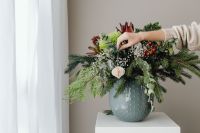 Kaboompics - Hand Arranging Evergreen Branches in Ceramic Vase