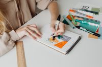 Kaboompics - Graphic Designer Coloring a Sketchbook Illustration with Teal and Orange Markers