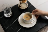 Kaboompics - Hand Moving a Coffee Cup on Black Slate Table