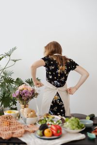 Kaboompics - Woman Tying Apron in Bright Kitchen with Copy Space