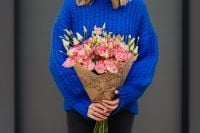 Kaboompics - Close up of woman holding bouquet of pink lisianthus flowers wrapped in brown paper