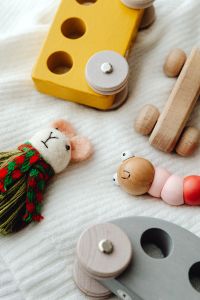 Kaboompics - Wooden Shape Puzzle and Handmade Bead Caterpillar on White Blanket