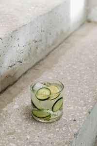 Kaboompics - Centered Glass of Cucumber-Lime Detox Water with Ice on Concrete Steps, Vertical Summer Drink Photo