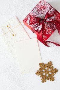 Kaboompics - Snow-Dusted Red Gift and Blank Holiday Card Styled with a Gold Snowflake