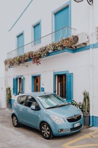 Kaboompics - Small Blue Car Parked Beneath a Flowering Balcony