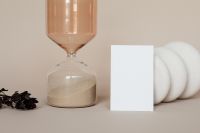 Kaboompics - Business Card Mockup Beside Amber Hourglass and White Sculptural Decor, Beige Branding Still Life