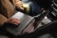 Kaboompics - Woman Typing on a Laptop and Holding Iced Matcha in a Car