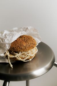 Kaboompics - Pearl Necklace Beneath Sesame Bun on Metal Plate