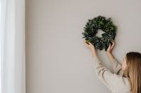 Kaboompics - Woman Holding Christmas Wreath Against Neutral Wall