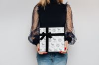 Kaboompics - Woman in Black Top with Sheer Polka-Dot Sleeves Holding a Reindeer-Print Christmas Gift