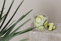 Kaboompics - Cucumber Water with Ice and Fresh Cucumber Sticks on Speckled Stone, Long Green Leaves in a Summer Drink Still Life