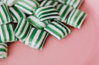 Kaboompics - Green and White Striped Sugar-Coated Candy on a Soft Pink Background