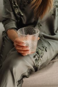 Kaboompics - Woman in Embroidered Satin Pajamas Holding a Textured Glass at Home