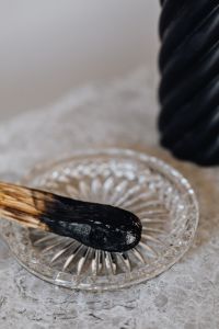 Kaboompics - Macro Palo Santo Incense on Glass Dish beside Black Candle, Marble Texture