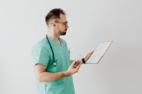 Kaboompics - Doctor Looking at Clipboard in Studio