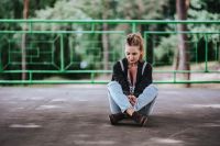 Kaboompics - Blonde woman in a black jacket and ripped jeans by a green handrail