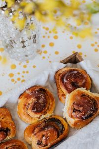 Kaboompics - Cinnamon Rolls with Forsythia and Glass Vase for Bright Spring Bakery Styling