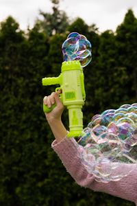 Kaboompics - Hand Holding a Green Bubble Blaster against Dark Garden Foliage