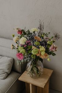 Kaboompics - Mixed Bouquet Against Textured Neutral Wall in a Dark Vase