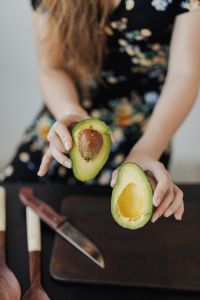 Kaboompics - Woman Holding Avocado Halves beside Kitchen Knife for Salad Prep