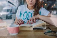 Kaboompics - Young Woman Reading an Open Book with Coffee in a Coffee Shop