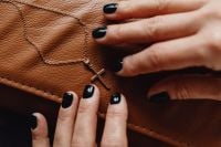 Kaboompics - Hands Reaching for a Gold Cross Necklace on Leather