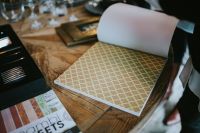 Kaboompics - Gold Geometric Wallpaper Sample Unrolled on Rustic Wood with Paper Roll