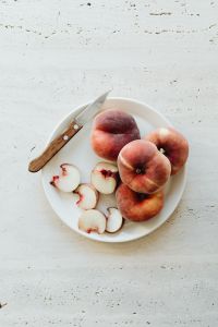 Kaboompics - Top View of Whole and Sliced Peaches with Knife on Light Table