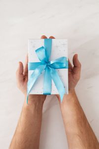 Kaboompics - Hands Holding Blue-Ribbon Christmas Present with Wide Marble Copy Space