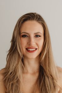 Kaboompics - Smiling Woman Looking at Camera Against a Neutral Wall