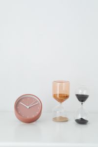 Minimalist Desk Still Life with Pink Clocks, Glass Hourglasses and Rose-Gold Eyeglasses on White