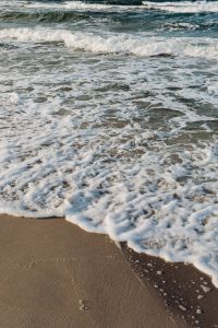 Kaboompics - Vertical Close-Up of Baltic Surf Foam Spreading Across Beach Sand