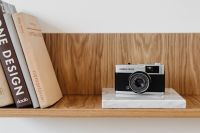 Kaboompics - Close-Up of Olympus Film Camera beside Design Books on Oak Shelf